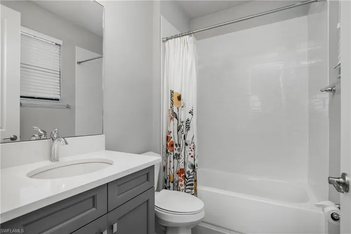 Bathroom featuring shower / bathtub combination with curtain and vanity