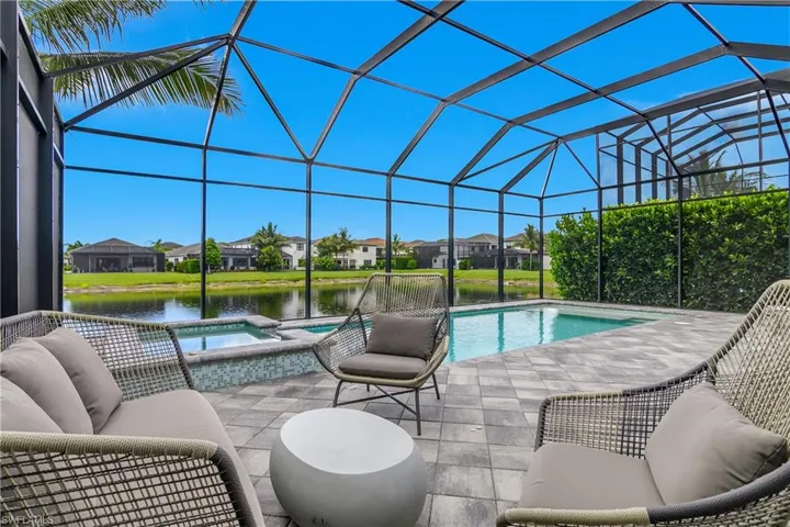 View of swimming pool with a sunroom, a residential view, a pool with connected hot tub, a patio area, and glass enclosure