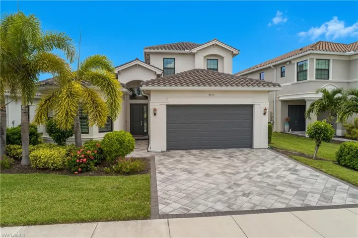 Mediterranean / spanish-style house with a garage, decorative driveway, a tiled roof, a front lawn, and stucco siding