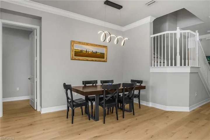 Dining room with stairway, crown molding, and light wood-style floors