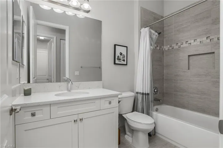 Bathroom featuring shower / tub combo, vanity, and light tile patterned floors