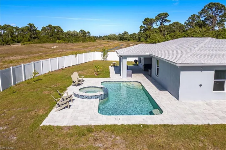 View of pool with a fenced backyard, a pool with connected hot tub, a patio, and a yard