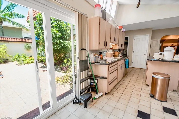 Kitchen featuring high vaulted ceiling, dishwasher, light tile floors, and light brown cabinets