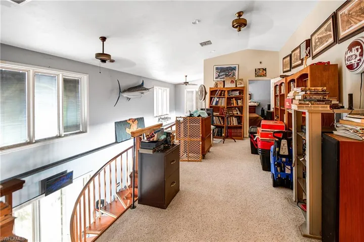 Carpeted office featuring ceiling fan and lofted ceiling