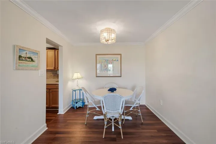 Dining area featuring wood-finish flooring, crown molding, and a drum pendant light fixture