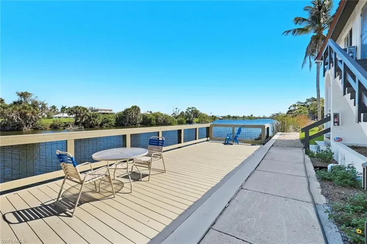 Waterfront deck featuring a composite surface, white railing with mesh infill, and a palm tree
