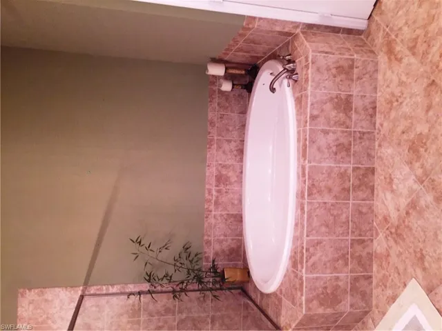 Bathroom featuring a white oval bathtub with chrome fixtures, surrounded by tiled walls and flooring