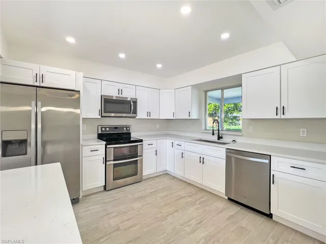 Kitchen with white cabinets, appliances with stainless steel finishes, sink, and light hardwood / wood-style floors
