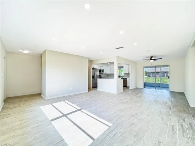 Unfurnished living room featuring sink, ceiling fan, and light hardwood / wood-style flooring