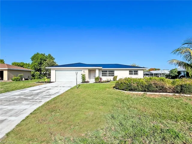 Single story home featuring a garage and a front yard