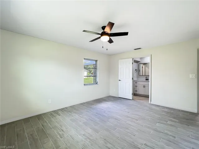Unfurnished bedroom with light wood-type flooring, ensuite bathroom, and ceiling fan