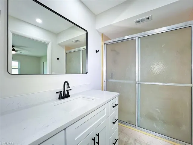 Bathroom featuring a shower with door, vanity, tile flooring, and ceiling fan
