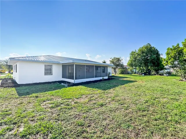 Rear view of house featuring a sunroom and a yard