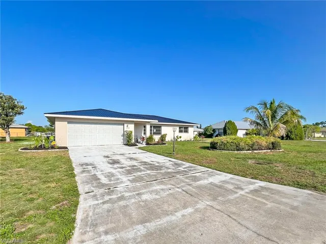 Ranch-style house featuring a garage and a front lawn