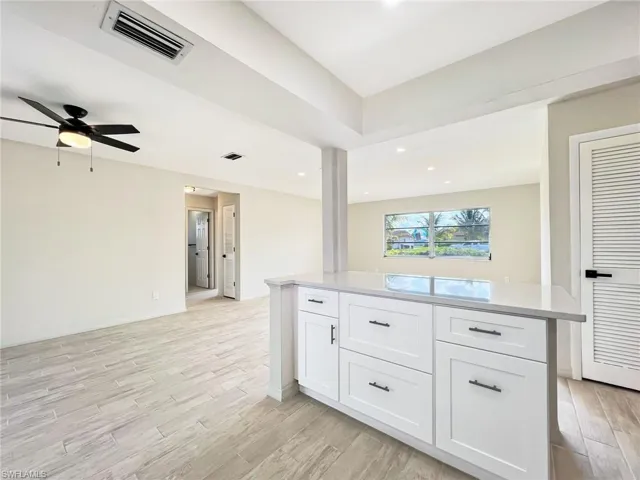 Kitchen featuring light hardwood / wood-style floors, white cabinetry, ceiling fan, and a kitchen island
