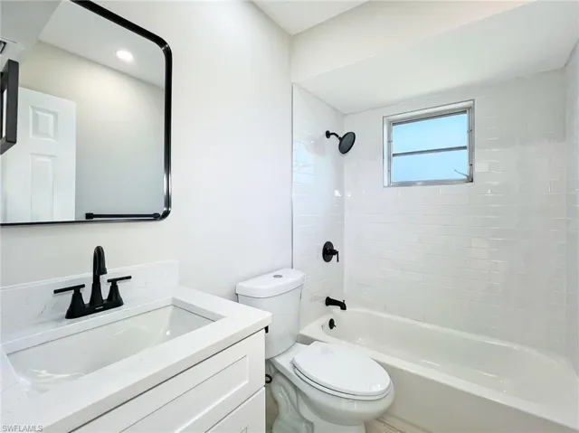Full bathroom featuring tiled shower / bath, oversized vanity, and toilet