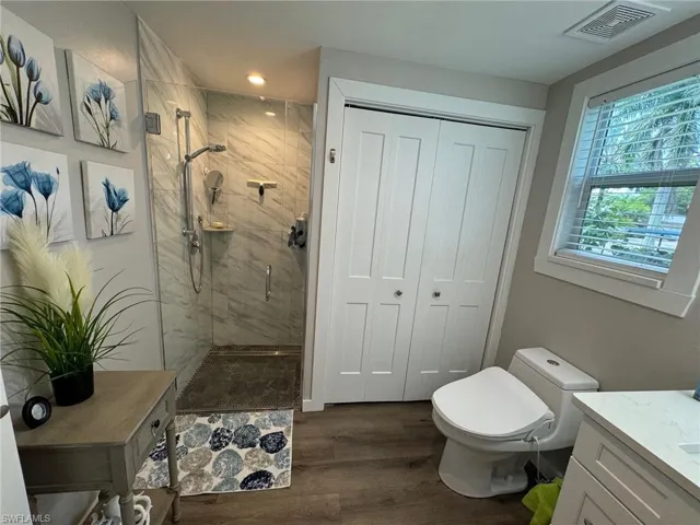Bathroom with toilet, wood-type flooring, an enclosed shower, and vanity