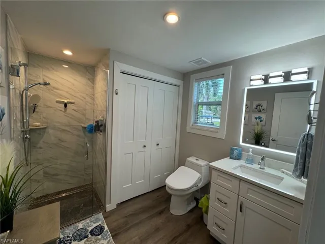 Bathroom with toilet, wood-type flooring, an enclosed shower, and vanity