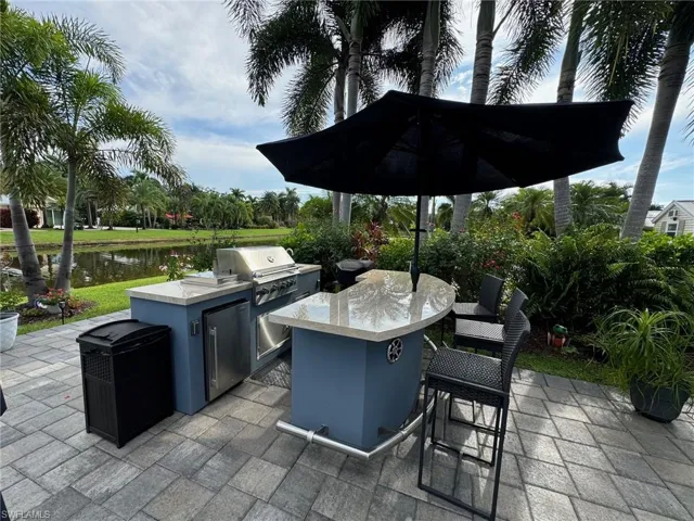 View of patio featuring a water view, an outdoor kitchen, and a grill