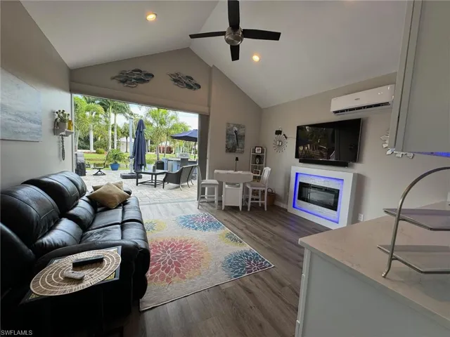 Living room with ceiling fan, a wall unit AC, high vaulted ceiling, and dark hardwood / wood-style flooring