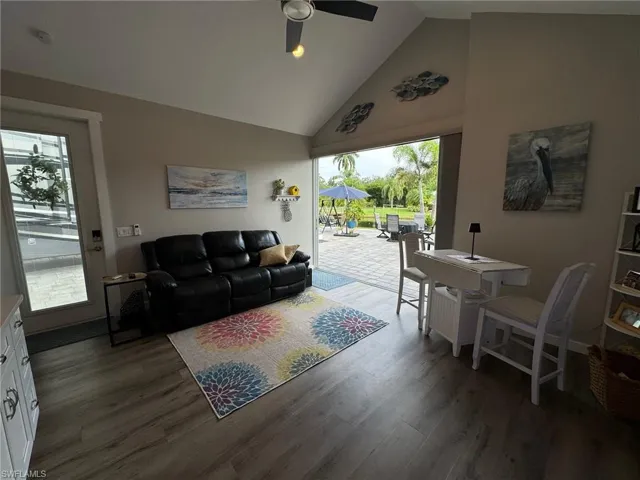 Living room with dark hardwood / wood-style flooring, high vaulted ceiling, and ceiling fan