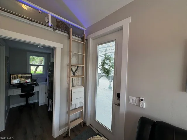 Doorway featuring lofted ceiling, a wealth of natural light, and dark hardwood / wood-style floors