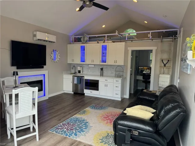 Living room featuring vaulted ceiling, dark hardwood / wood-style flooring, sink, ceiling fan, and an AC wall unit