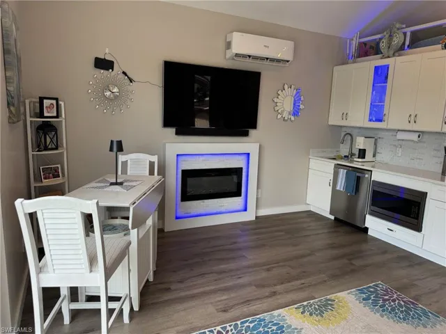 Kitchen featuring a wall unit AC, tasteful backsplash, stainless steel appliances, dark wood-type flooring, and white cabinets