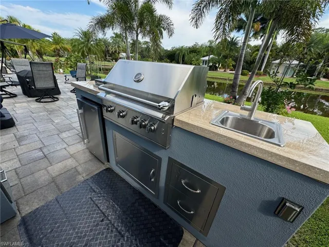 View of patio with a grill, sink, an outdoor kitchen, and a water view