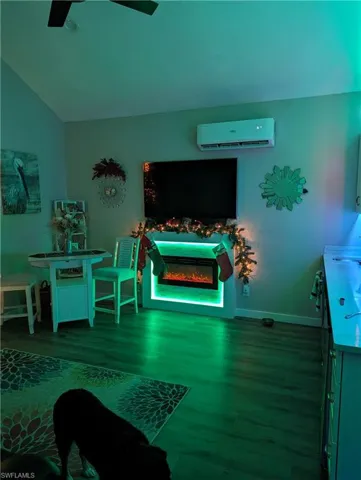 Recreation room featuring ceiling fan, lofted ceiling, a wall mounted air conditioner, and wood-type flooring