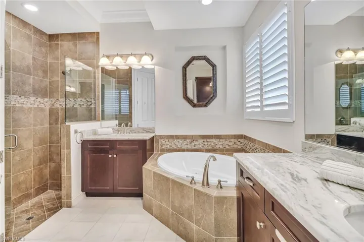 Bathroom with double vanity, shower with separate bathtub, and tile patterned floors