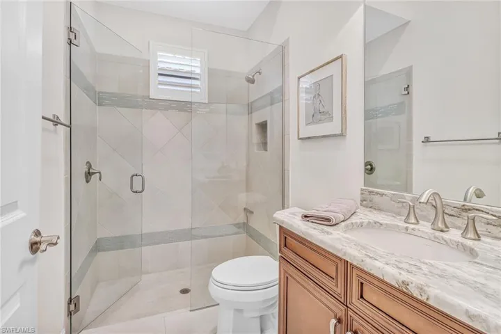 Bathroom with a shower with door, toilet, and vanity