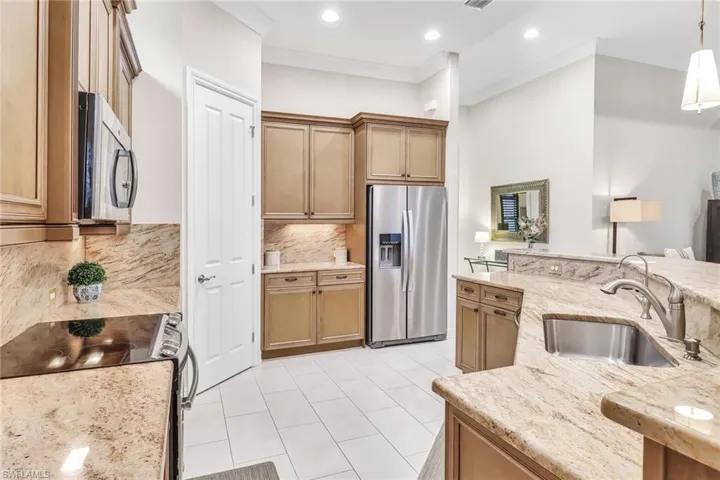 Kitchen featuring stainless steel appliances, sink, decorative light fixtures, light tile patterned floors, and decorative backsplash