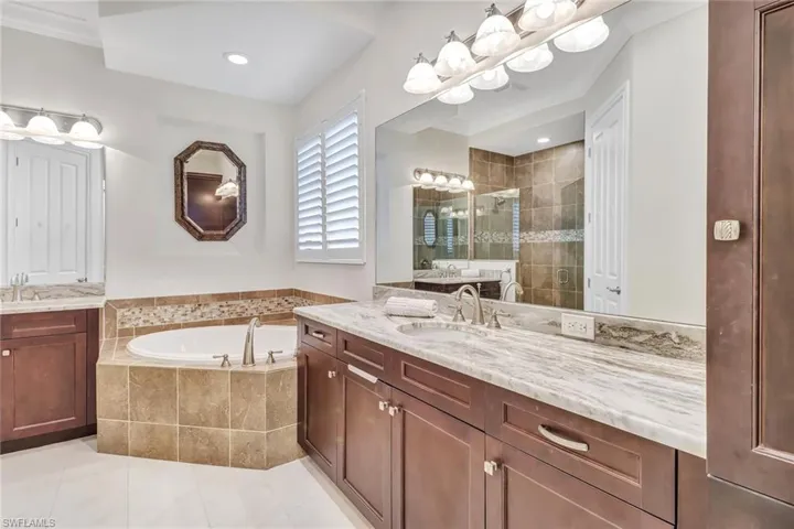Bathroom with tile patterned flooring, shower with separate bathtub, and double vanity