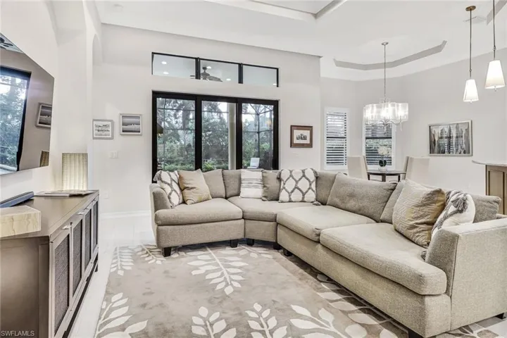 Living room with light tile patterned floors, a tray ceiling, a wealth of natural light, and a high ceiling