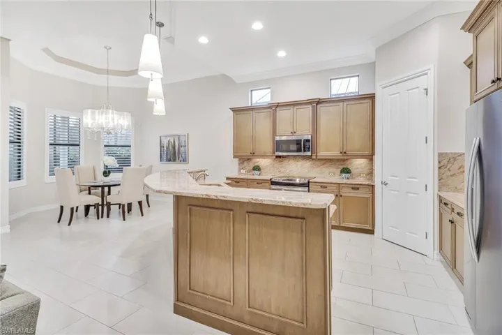 Kitchen featuring appliances with stainless steel finishes, tasteful backsplash, a wealth of natural light, decorative light fixtures, and light tile patterned floors
