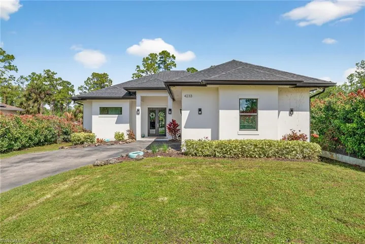 Prairie-style home featuring a front yard, stucco siding, and roof with shingles