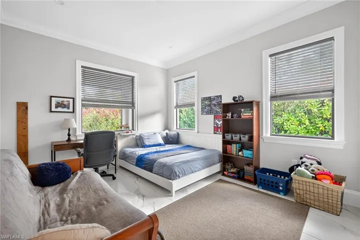 Bedroom with ornamental molding and marble look tile flooring