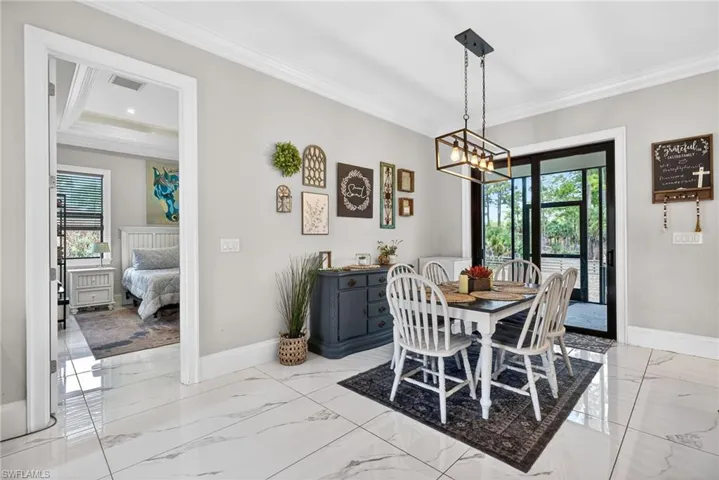 Dining space featuring ornamental molding, hanging lights, and light marble finish floors