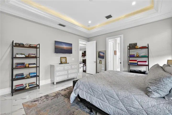 Bedroom featuring ornamental molding, light marble finish flooring, a tray ceiling, and recessed lighting