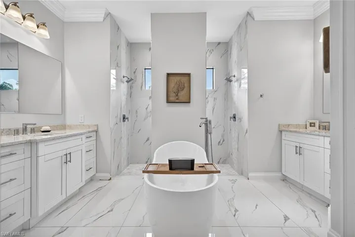Bathroom featuring healthy amount of natural light, a marble finish shower, ornamental molding, and a soaking tub