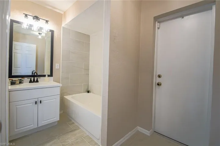 Bathroom with a bathtub, tile flooring, and large vanity