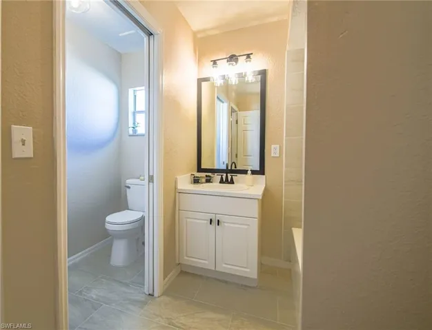 Bathroom featuring vanity with extensive cabinet space, tile flooring, and toilet
