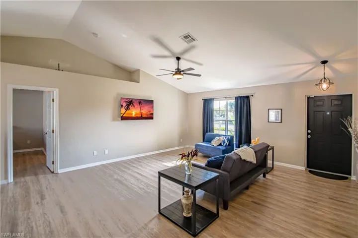 Living room featuring wood-type flooring, ceiling fan, and vaulted ceiling