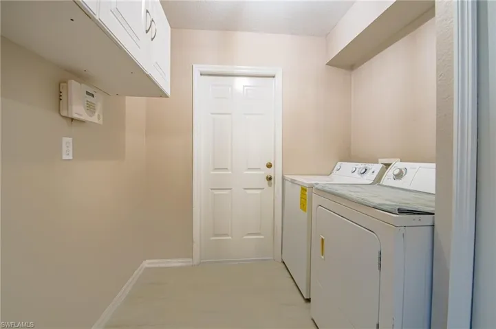 Laundry area with cabinets, light tile flooring, and washer and clothes dryer