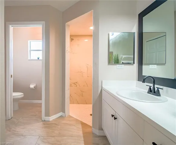 Bathroom featuring tile floors, a shower, vanity with extensive cabinet space, and toilet