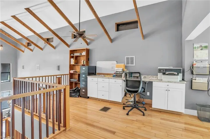 Office area featuring light hardwood / wood-style flooring, ceiling fan, and high vaulted ceiling