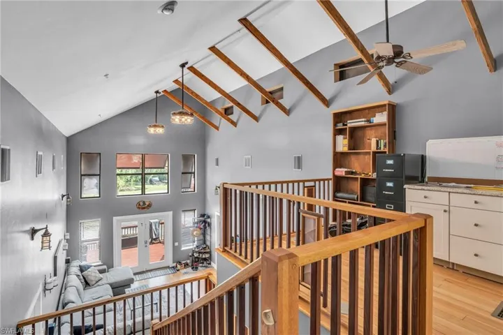 Hallway with high vaulted ceiling and light hardwood / wood-style floors