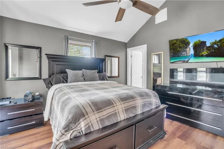 Bedroom featuring high vaulted ceiling, wood-type flooring, and ceiling fan