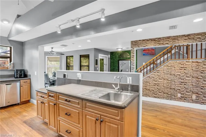 Kitchen with sink, ceiling fan, light hardwood / wood-style floors, and stainless steel dishwasher
